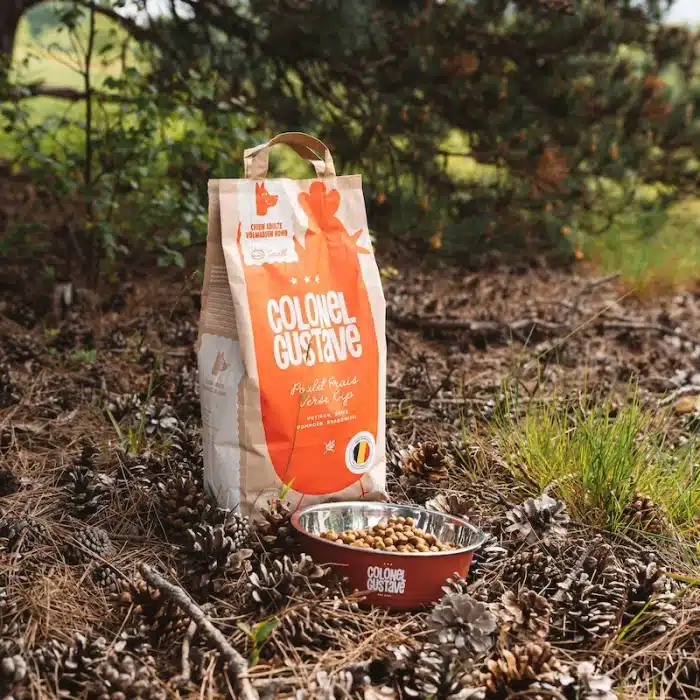 Sac Colonel Gustave au poulet posé en forêt à côté d'une gamelle de croquettes